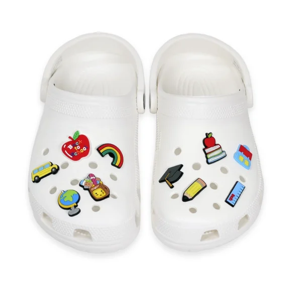 White Crocs with Back to School shoe charms, including an apple, books, school bus, pencil, ruler, graduation cap, and educational-themed designs.
