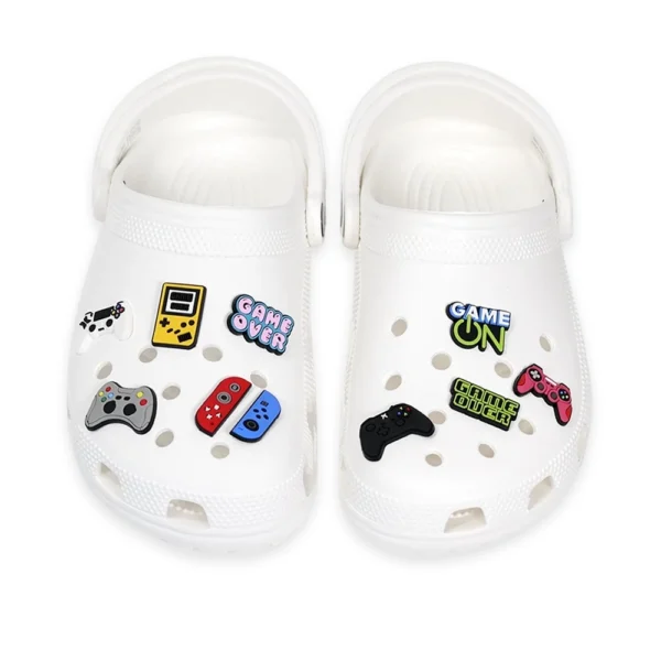 White footwear decorated with gaming-themed charms, including video game controllers, handheld consoles, and "Game Over" text