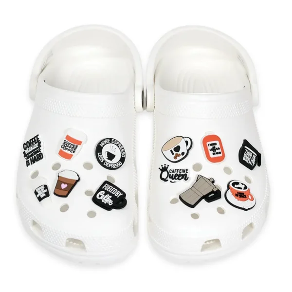 White footwear decorated with coffee lover charms, including espresso cups, caffeine-related phrases, and coffee mugs.