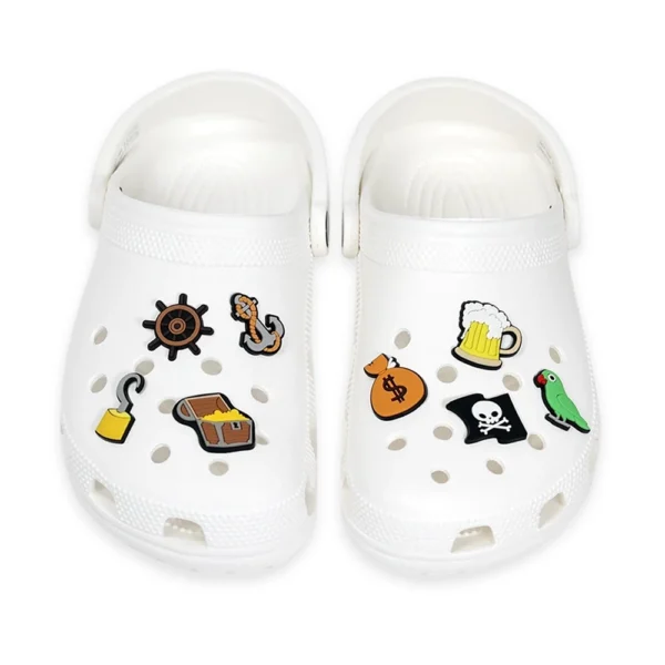 White footwear decorated with pirate-themed charms, including a treasure chest, pirate flag, anchor, ship wheel, and parrot