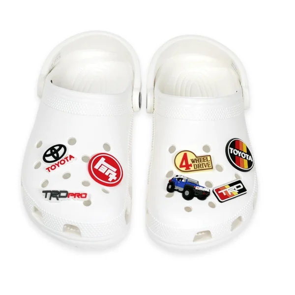 White Crocs decorated with Toyota FJ Cruiser Blue, Toyota logos, TRD Pro badge, and off-road 4x4 emblem shoe charms.