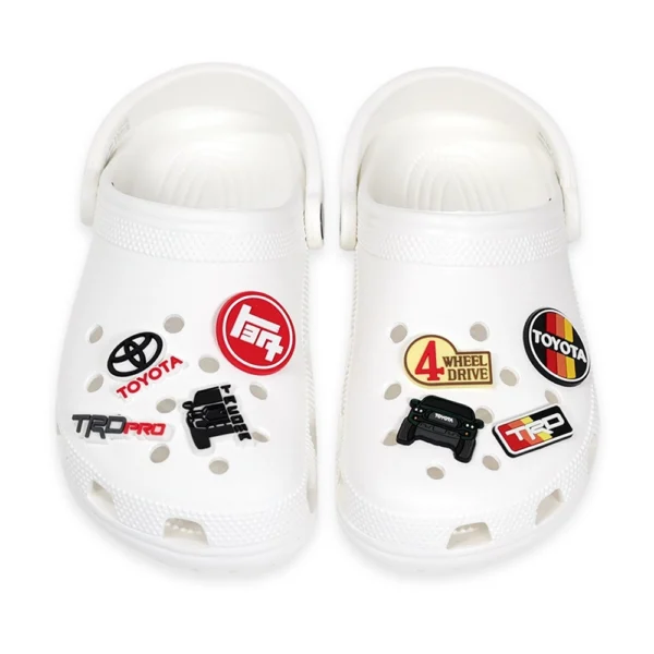 White Crocs decorated with Toyota Tacoma Green, Toyota logos, TRD Pro badge, and off-road 4x4 emblem shoe charms.
