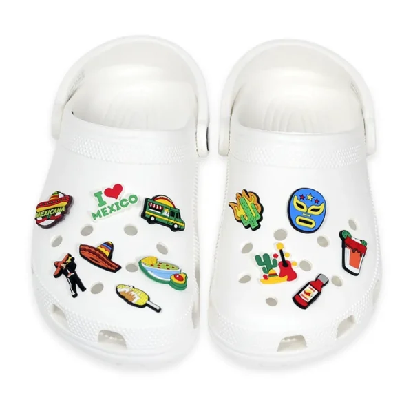 White footwear decorated with Mexican-themed charms, including a lucha libre mask, tacos, food truck, cactus, hot sauce, and mariachi elements.